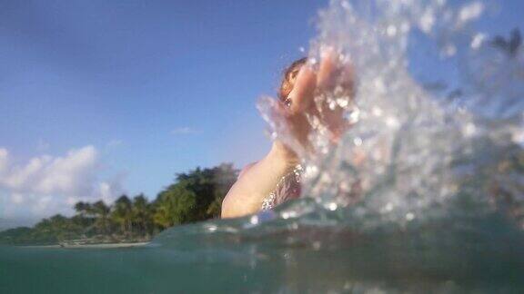 一名女子在大海中放松对着镜头泼水