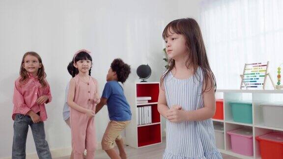 可爱的亚洲6岁女学生身穿蓝色条纹裙在她的朋友面前跳舞两个可爱的小男孩拉着他们的手欢快地跳着