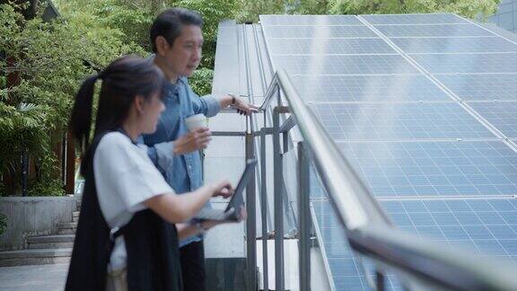 工程师看着数码平板电脑和同事讨论太阳能电池板的可再生能源