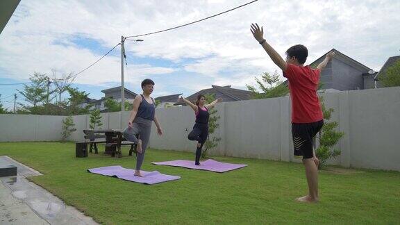 亚洲中国女人和男人在后院做瑜伽树的姿势