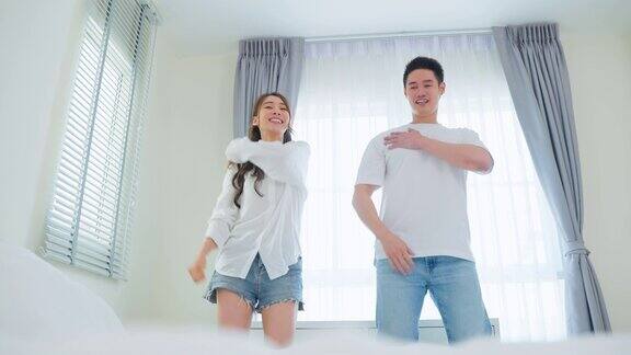 亚洲迷人的情侣在家里的卧室里一起跳舞年轻浪漫的新婚男女录制挑战视频虚拟剪辑唱歌音乐后从床上醒来的房子