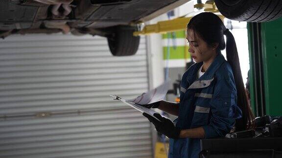 亚洲女性汽车修理工在汽车车间检查维修记录