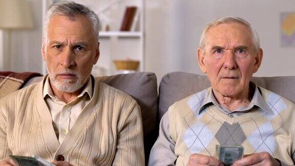 可怜的退休男子数着钱看着摄像机退休年龄增加了