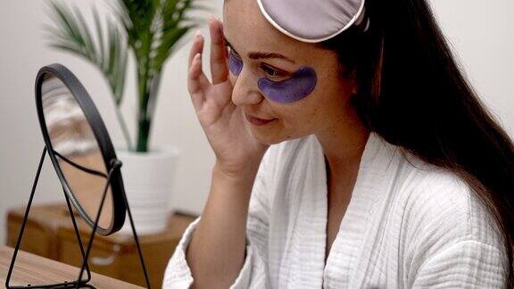 女人凝视着镜子用眼罩遮住皱纹、黑眼圈和眼罩
