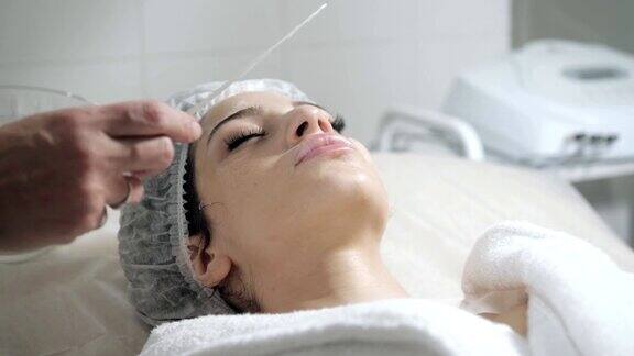 用抹刀去除脸上的泡沫年轻漂亮的女人正在美容院接受治疗洁面泡沫使用