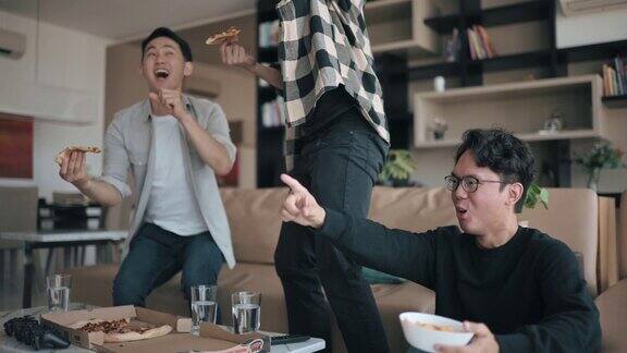 亚裔中国年轻人在家里和他的朋友们看电视上的体育比赛时为他的球队呐喊和欢呼当运动队赢得冠军时庆祝胜利朋友欢呼欢呼