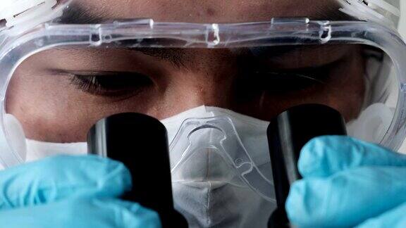 医学保健生物学病毒检测药物治疗试验试验室配有医学专家穿着白色防护服俯视显微镜