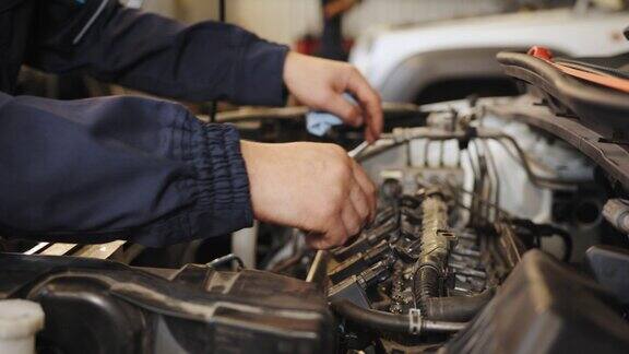 近距离的手无法识别的机制年轻的汽车修理工在车间的展台上拆卸对面的发动机进行诊断和修理汽车修理工在汽车修理厂工作维修服务