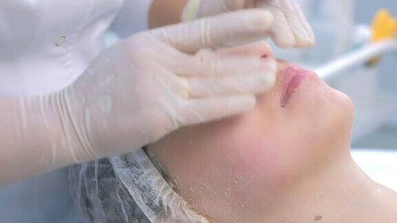 美容师做面部按摩脱皮面膜在女人的脸上特写