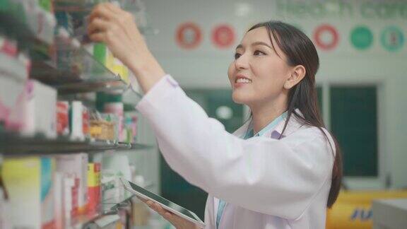一位亚洲女性药剂师穿着实验服在一家现代药店使用药片分析医疗数据