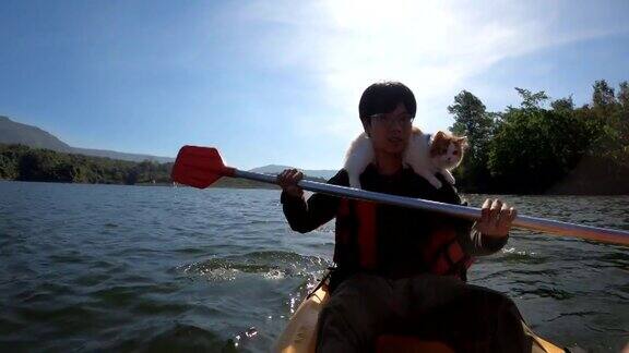 一个年轻人肩上扛着一只猫在湖中划皮划艇
