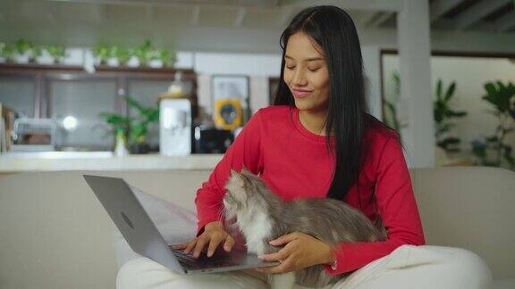 年轻的亚洲女人和她的猫坐在客厅里