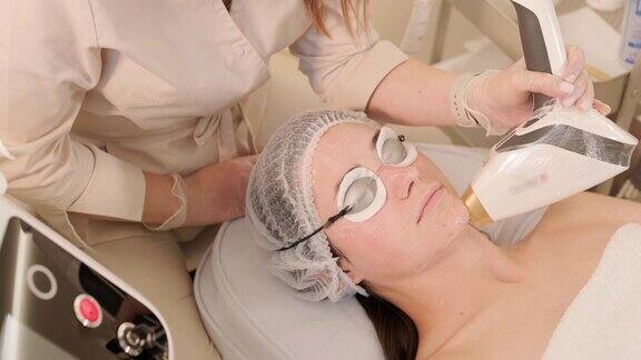 一名妇女在美容中心接受眼部周围的射频提拉手术以恢复面部皮肤的活力