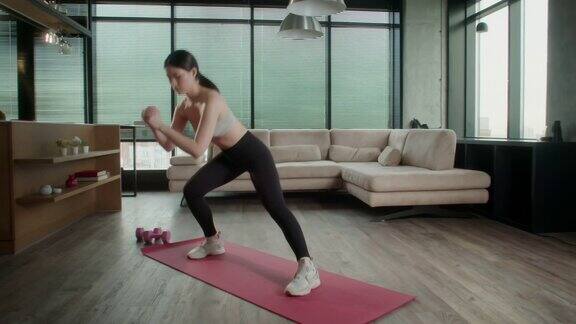 运动的亚洲妇女在运动服工作在家年轻迷人的女性在客厅的红色健身垫上健身在家里进行保健和运动心理治疗