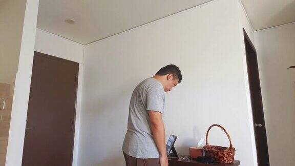 亚洲华人中年男子用哑铃锻炼在家锻炼晚上在客厅用平板电脑锻炼