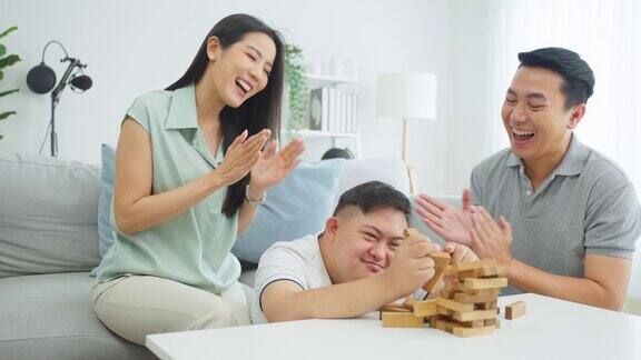 亚洲漂亮的夫妇和他们的儿子在客厅下棋快乐的家庭年轻的家庭感觉快乐和放松一起度过自由的闲暇时间关系生活方式