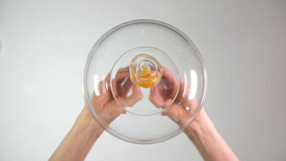 从下面看一个鸡蛋被打碎并倒进一个玻璃碗里60便士