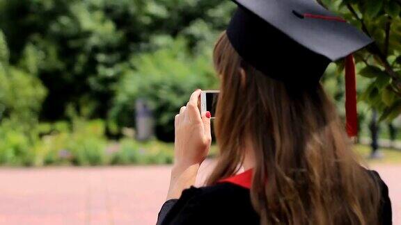 戴着毕业帽的女性在公园用智能手机拍摄朋友
