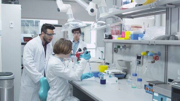 身穿大衣的多民族学生团队在化学教室实验室工作