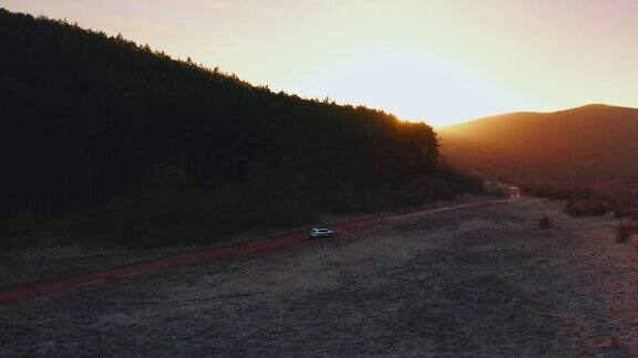 在金色的夕阳下一辆SUV行驶在空旷的乡村道路上