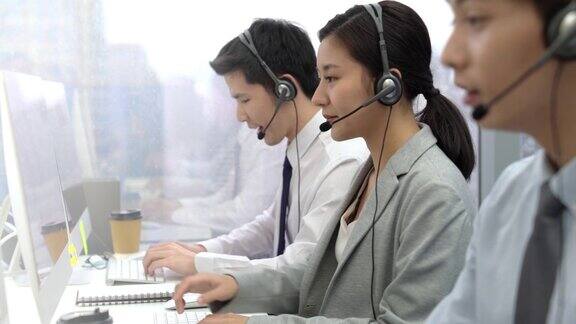 亚洲女商人戴着耳机和团队在呼叫中心工作