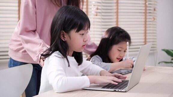 亚洲孩子享受家庭与在线会议在家里女童在笔记本电脑上学习和在线学习姐妹们坐在家里的客厅里使用笔记本电脑教育理念、技术理念