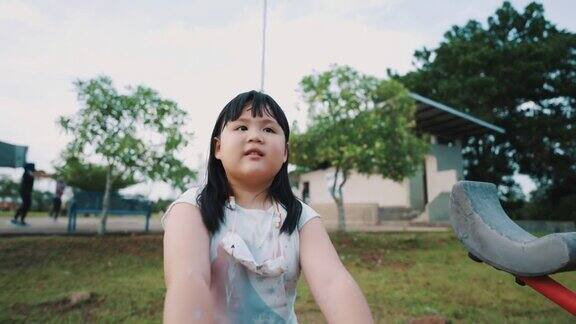亚洲小女孩正在户外游乐场玩跷跷板