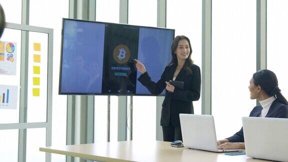 业务介绍东南亚在会议室的显示器上女商人向同事介绍加密货币投资