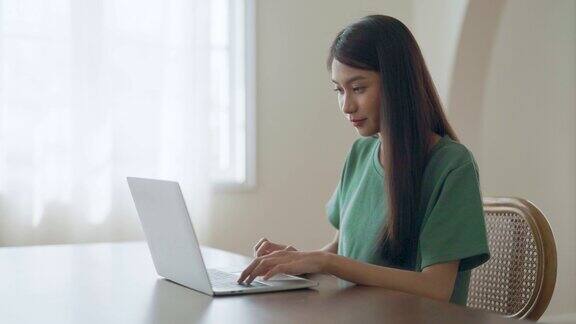 年轻的亚洲妇女在家里工作女性在家里的书桌上使用电脑笔记本电脑