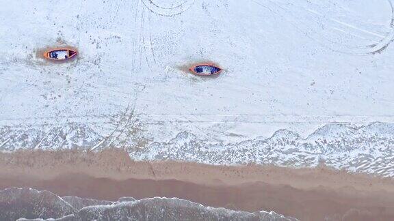 波罗的海白雪皑皑的海滩上的小船鸟瞰图的冬天