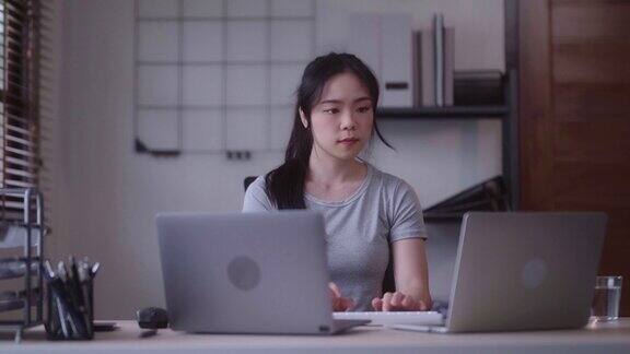 年轻的亚洲女性在家里用笔记本电脑分析图表和图表在家工作