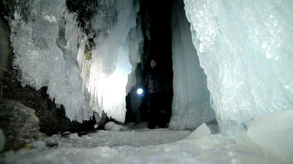 贝加尔湖冰洞上的旅行者冬岛之旅背包客正在冰洞中行走游客看着美丽的冰洞徒步旅行者穿银色夹克背包led灯