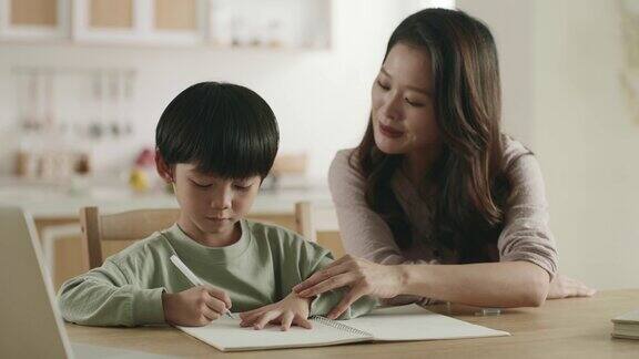 年轻的亚洲母亲在家辅导儿子