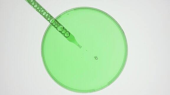 滴管从灰色背景的手表玻璃中吸取绿色液体