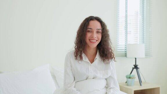 拉丁美人的肖像穿着睡衣微笑看着相机有魅力的年轻女性感到新鲜和快乐从床上早起在家里早上的卧室健康的生活方式
