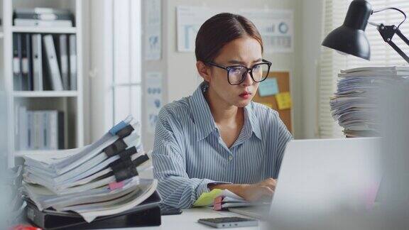 亚洲女性办公室职员在笔记本电脑上工作感觉压力很大办公室很忙