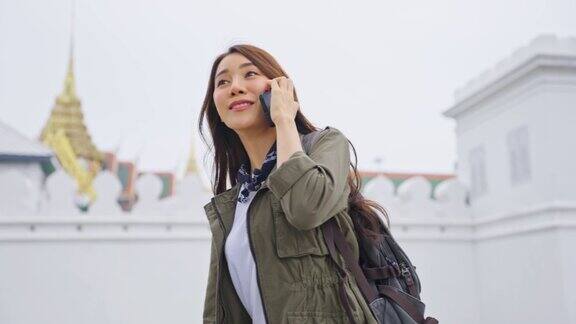 亚洲有吸引力的女人背包客在城市散步时打电话美丽的女人旅游旅行者独自在街上旅行使用智能手机享受花时间在泰国度假旅行