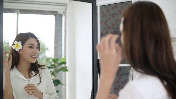 漂亮的年轻亚洲女人在镜子前化妆