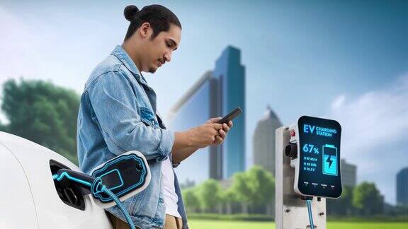 一名亚洲男子在电动汽车充电时等待使用智能手机细读