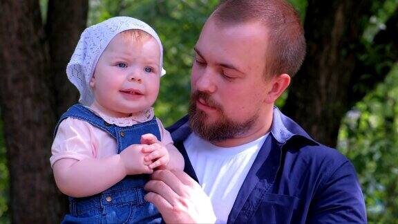 年轻的爸爸抱着女儿在城市公园散步全家福