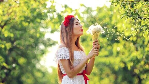 一束蒲公英飞起来降落伞飞起来在一个阳光明媚的日子里美丽的女孩在森林里吹着一束花肖像的观点
