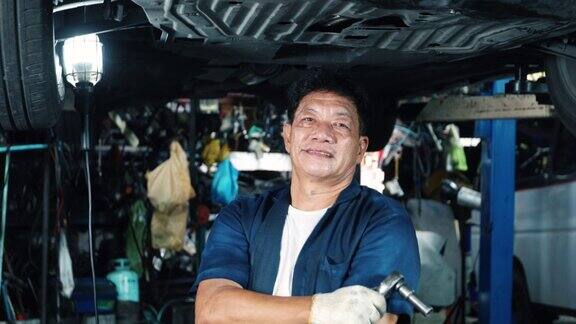 老年机械师在车库检查和修理汽车悬架