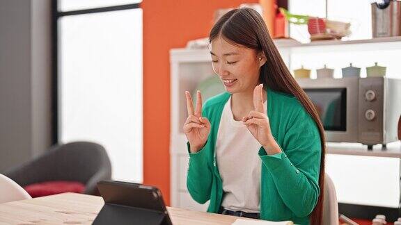 年轻的中国女子在餐厅用触控板上网上课
