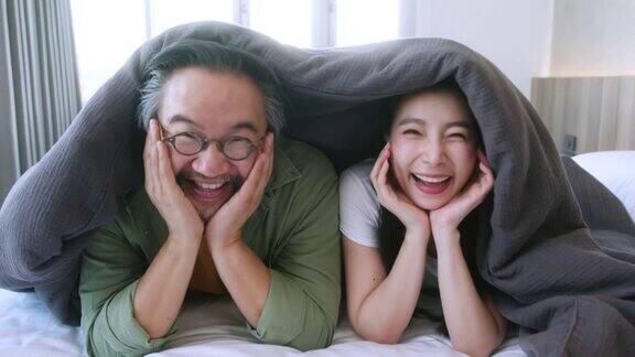 幸福亚洲的新婚夫妇手牵着脸一起和幸福快乐一起在床上的毯子下移动幸福的家庭观念