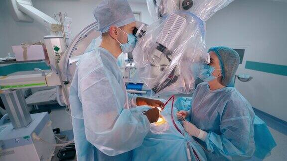 外科医生在手术中使用现代医疗设备医生和一名穿制服的护士在给病人做手术时看着显微镜