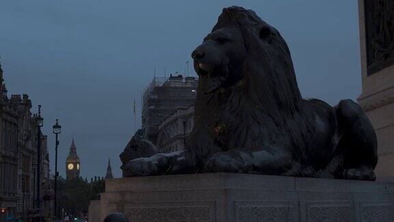 从特拉法加广场拍摄的标志性狮子雕像背景是大本钟在阴天的夜晚这是伦敦历史地标永恒的维多利亚地标