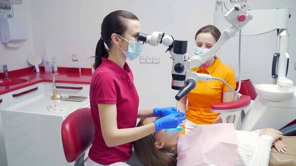 在现代牙科诊所女牙医带着助手用显微镜治疗牙齿特写视图