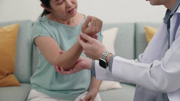 年轻的亚洲男性医生检查他的病人的手臂和关节的情况