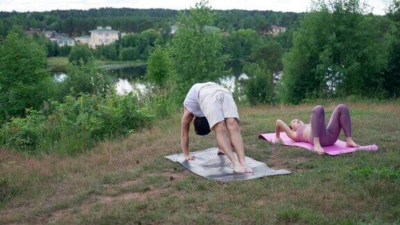 运动男男女女在河边的垫子上练习瑜伽