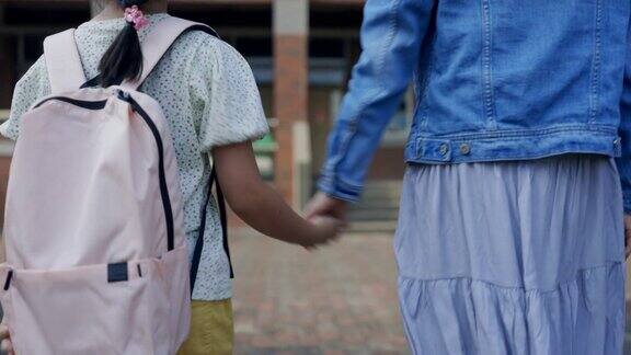 年轻的亚洲母亲带着她的小女儿去上学的背影